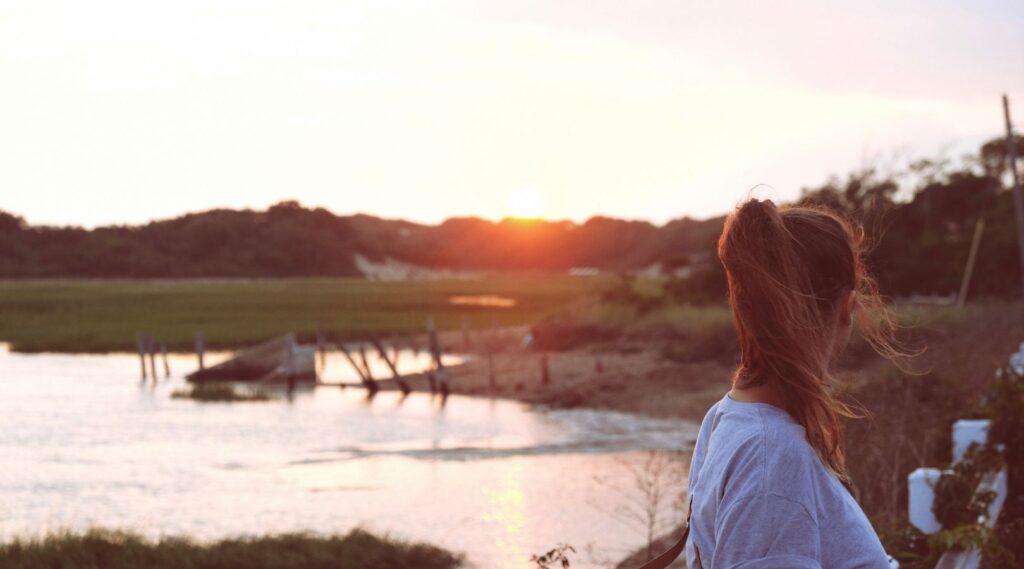 A post-secondary student situated beside a lake while thinking about eco-anxiety